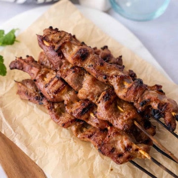 Feature image of grilled Thai Pork skewers on a plate.