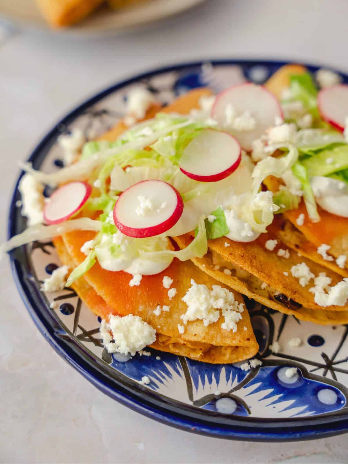 Tacos dorados on a plate with salsa and toppings.