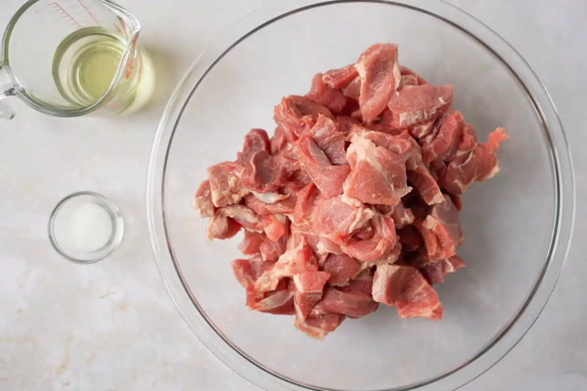 Sliced pork in a bowl with oil and salt on the side.