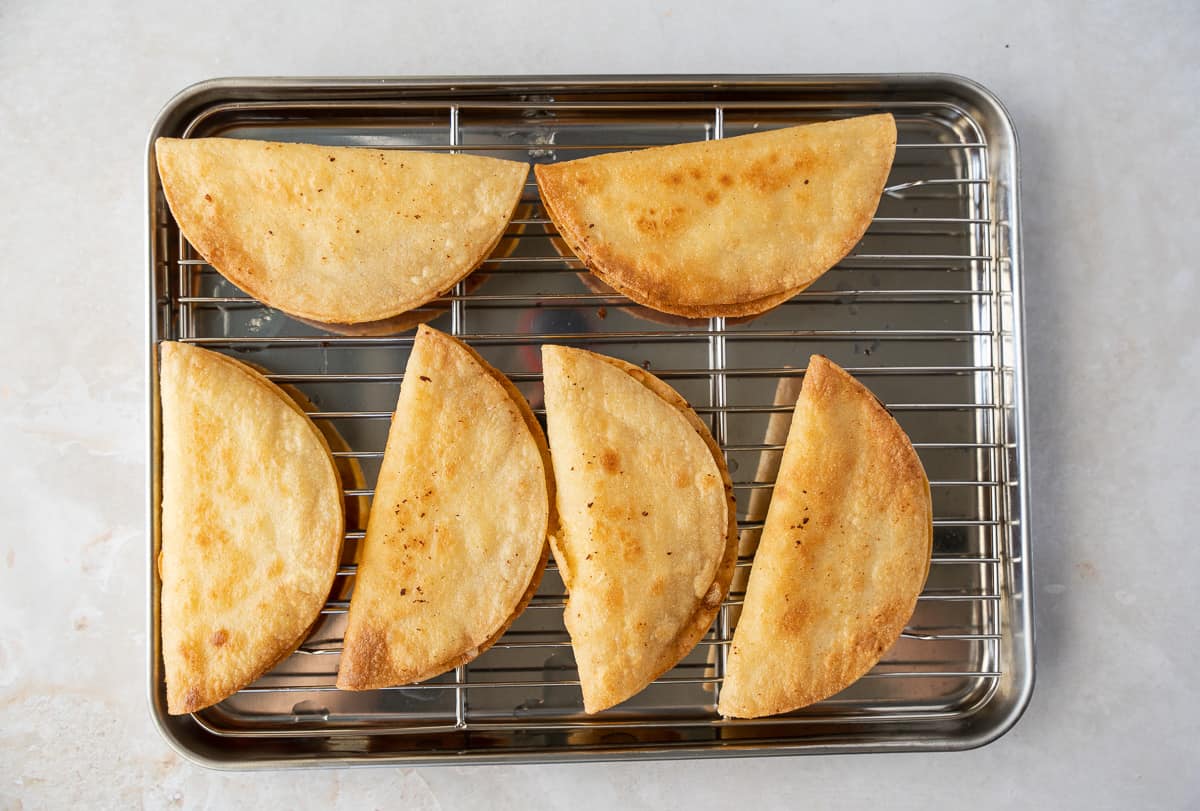 Fried tacos on a baking sheet.