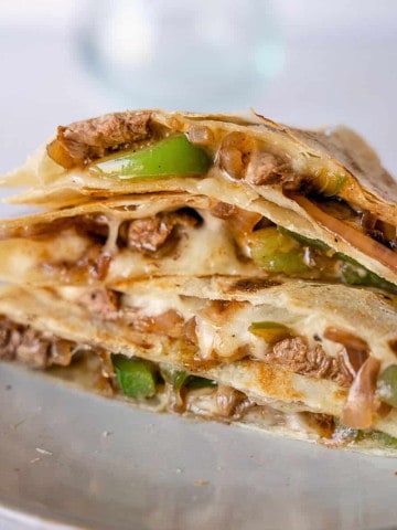 Up close view of steak fajita quesadilla stacked together on a plate.