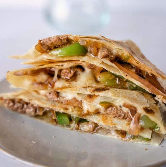 Up close view of steak fajita quesadilla stacked together on a plate.