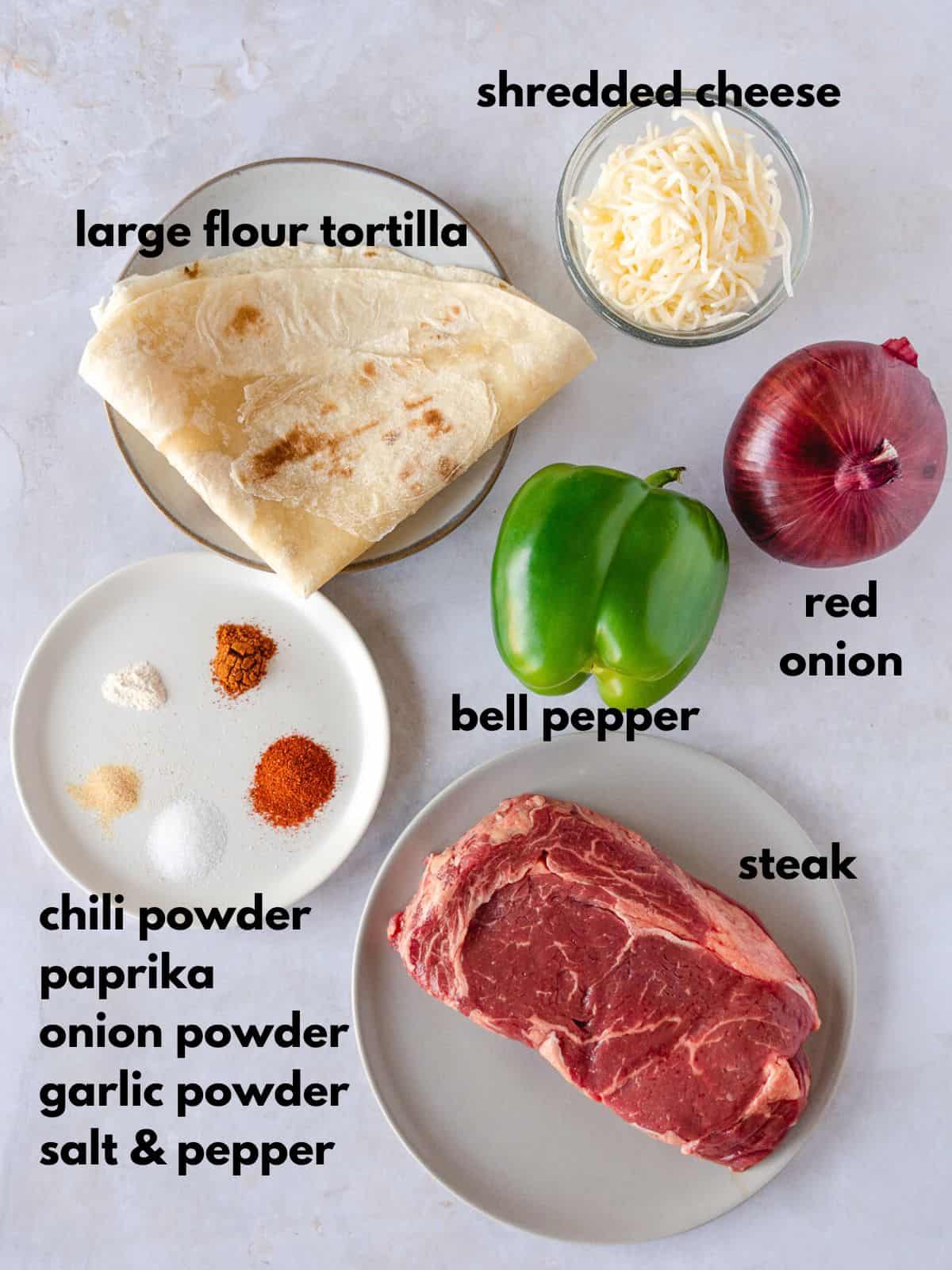 Ingredients labeled with text, shredded cheese, flour tortilla, bell pepper, red onion, steak, and seasoning.