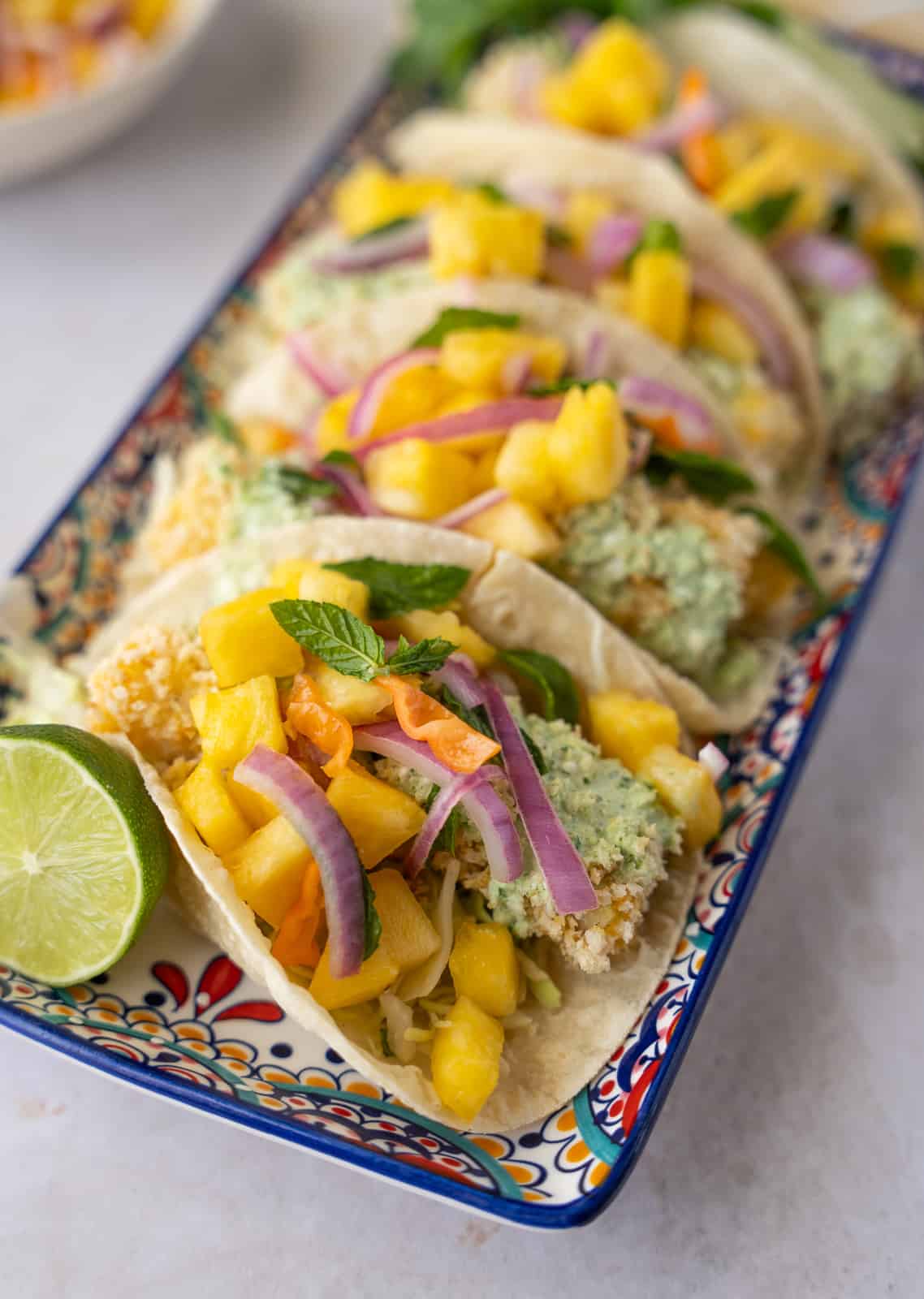 Fish tacos on a colorful plate topped with pineapple salsa.