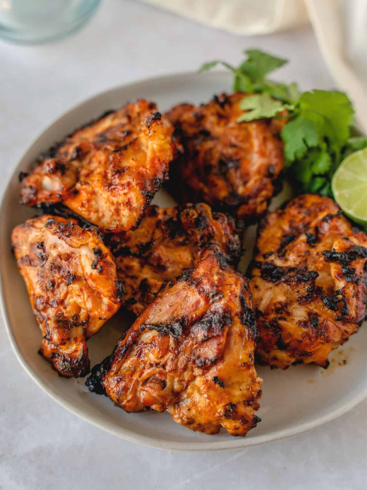 Grilled chicken on a plate with cilantro and lime.