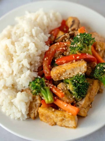 Feature image of teriyaki tofu and vegetable stir fry with a side of rice.