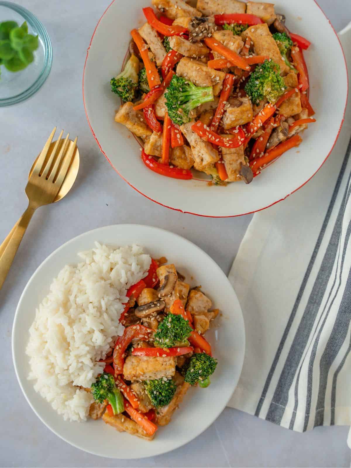 Two plates of teriyaki tofu vegetable stir fry.