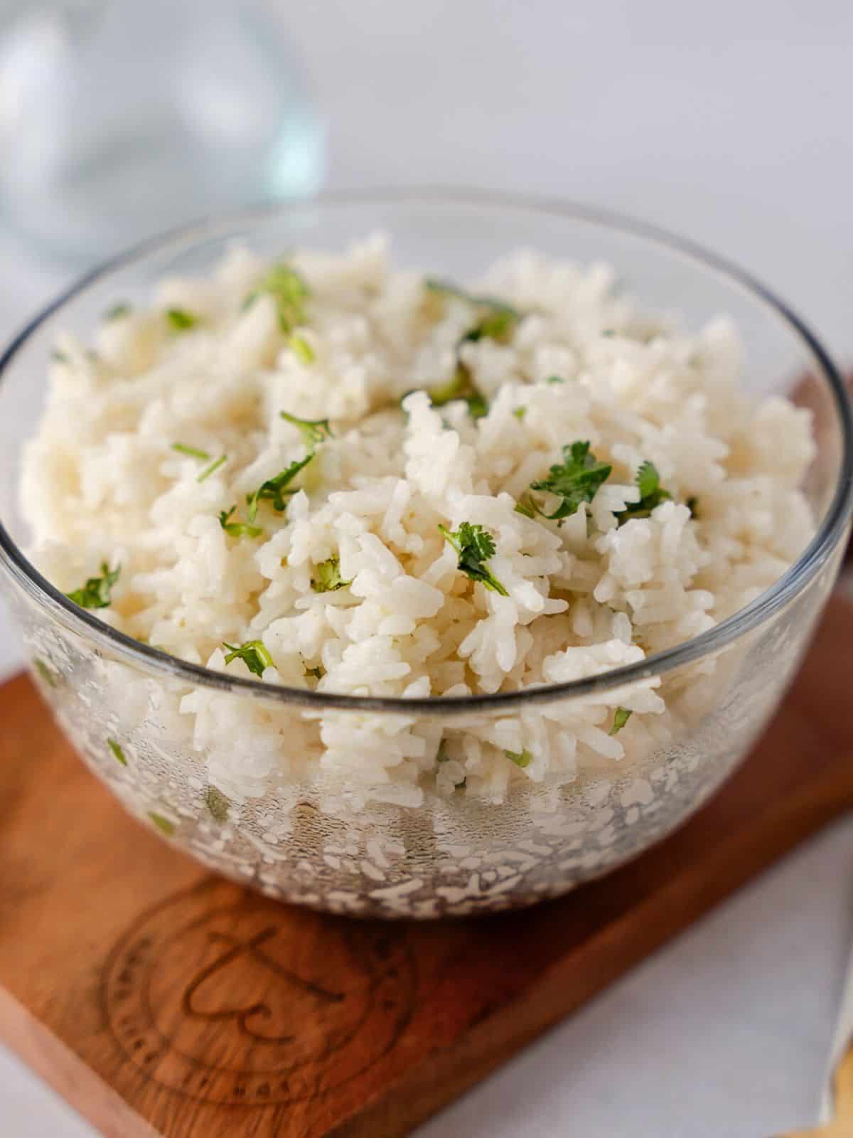 Coconut rice in a glass bowl on a small wooden board.