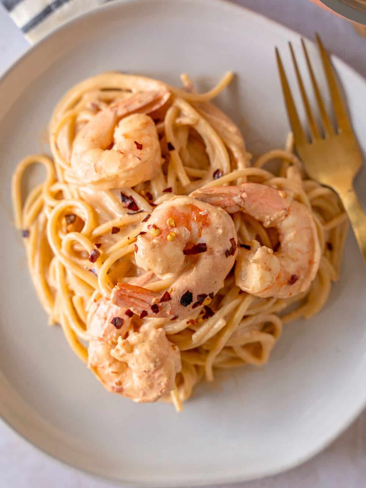 Spicy Chipotle pasta topped with shrimp on a plate with a gold fork.