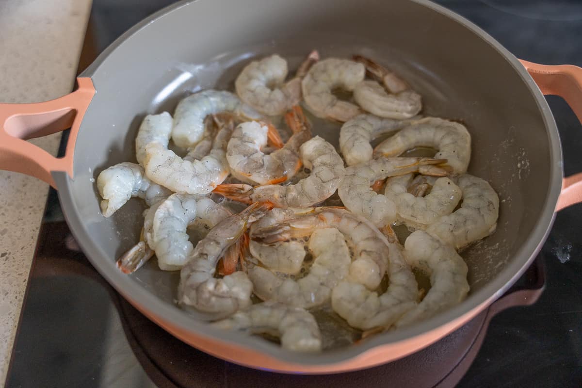 Raw shrimp being cooked in a skillet.