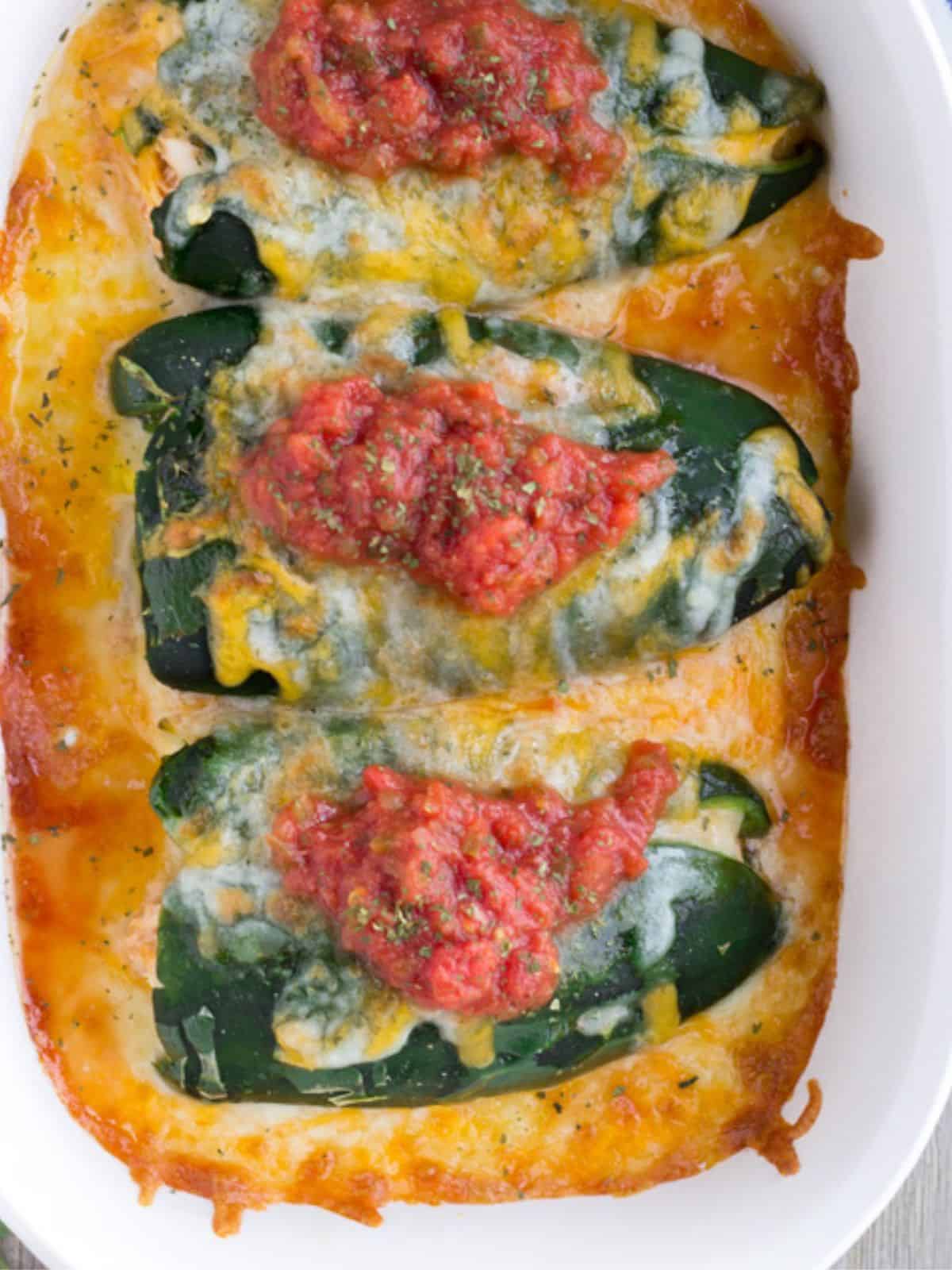 Baked chicken chili rellenos in a white casserole dish.