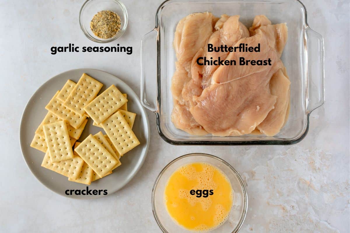 Ingredients with text labels: garlic seasoning, crackers, eggs, butterflied chicken breast.