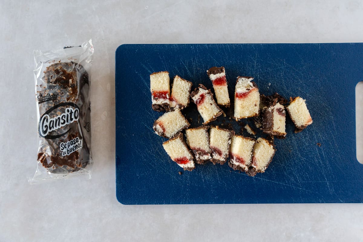 One whole gansito in it's package and one chopped up on a cutting board.