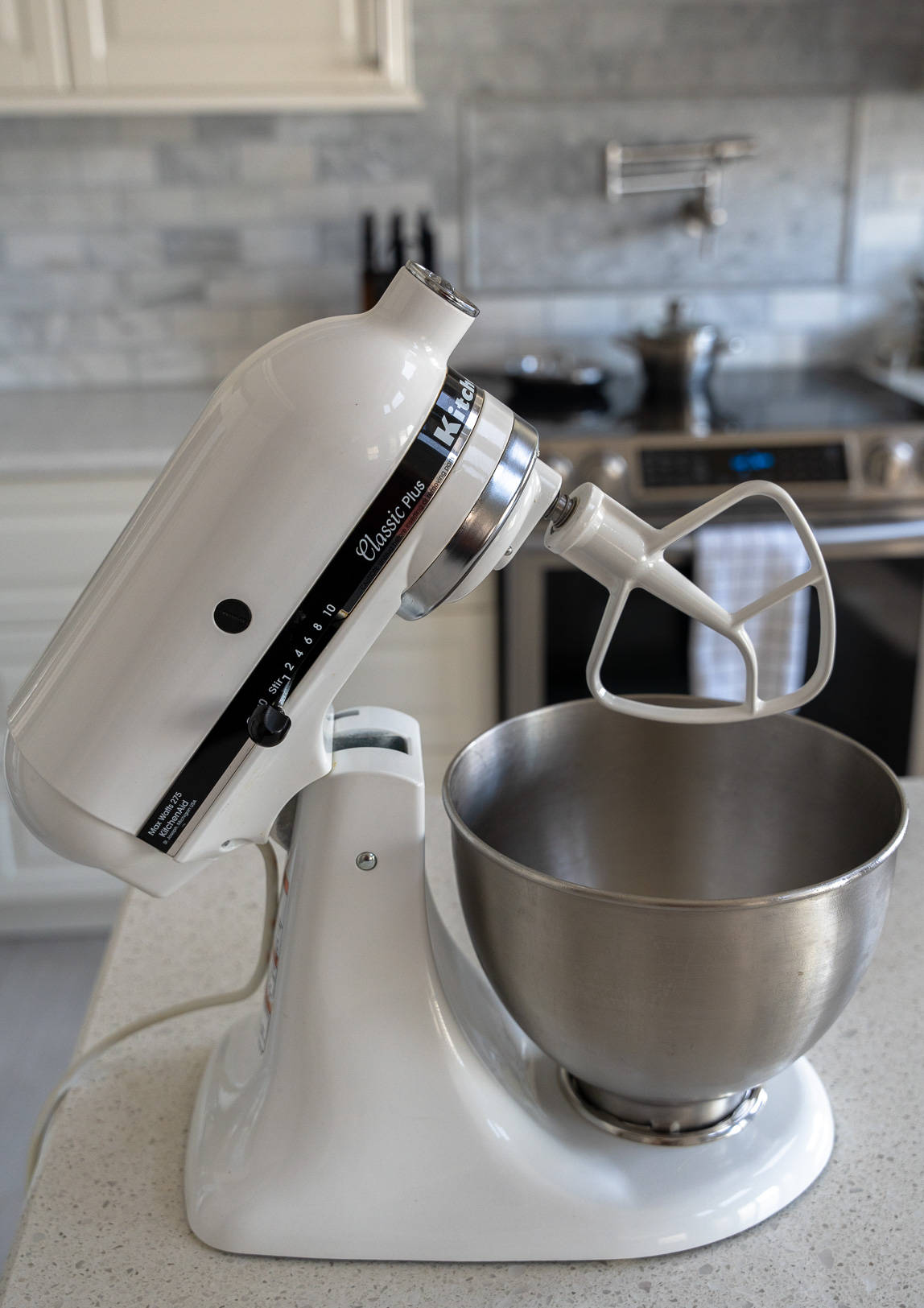 White stand mixer on the counter with a paddle attachment.