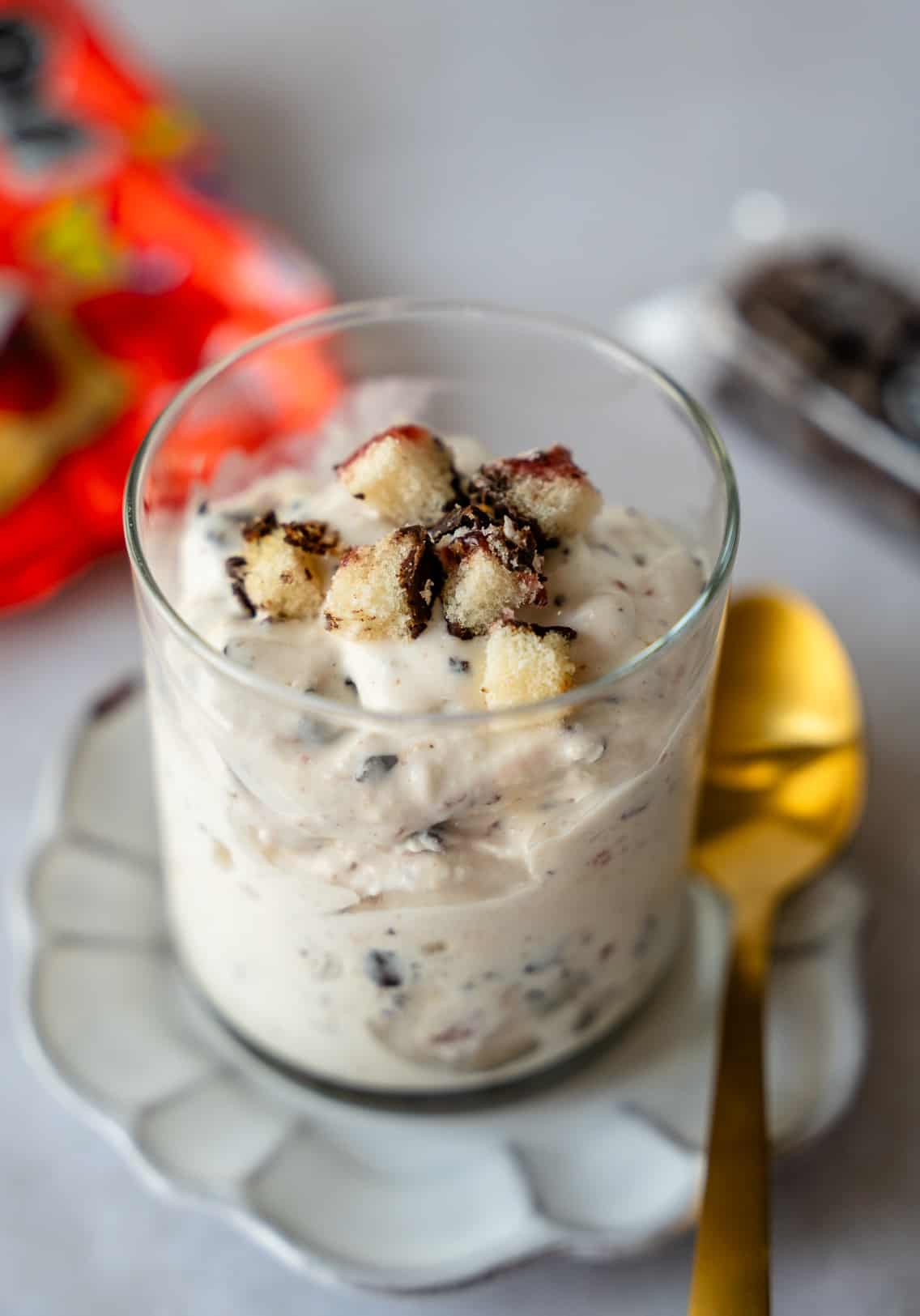 Ice cream in a glass cup with a gold spoon on the side and gansito pieces on top.