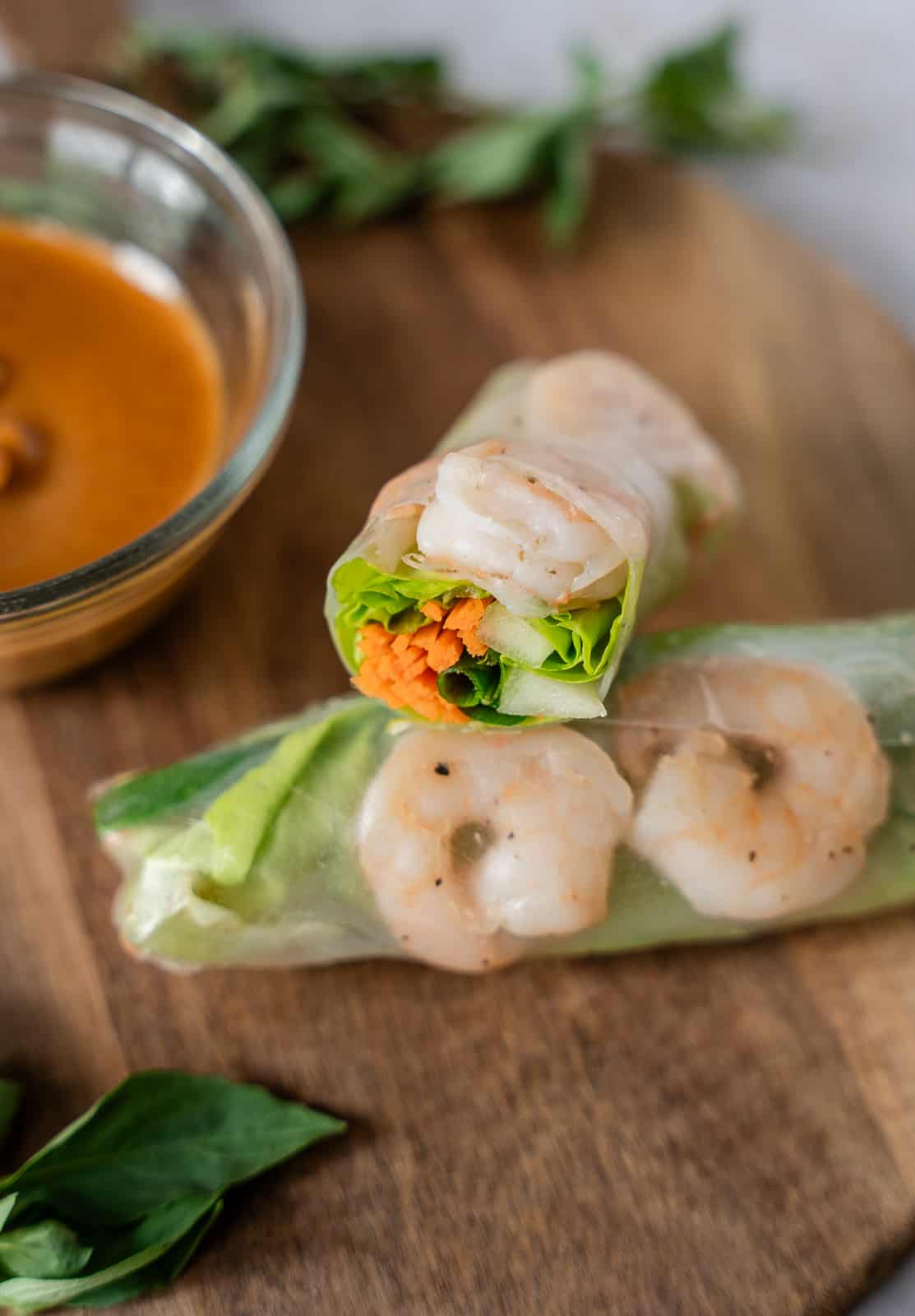 Two shrimp rice paper rolls, with one sliced in half to show the filling inside.