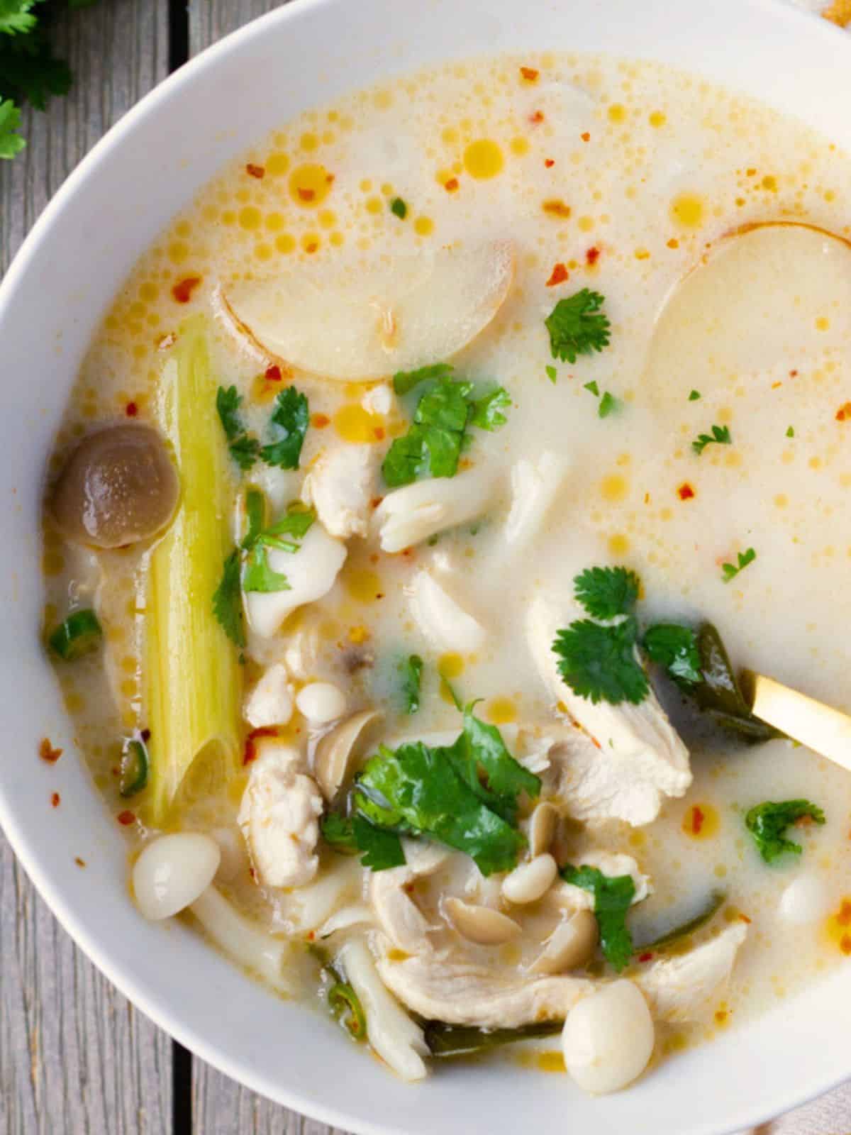 Thai coconut chicken soup in a bowl with a spoon inside.