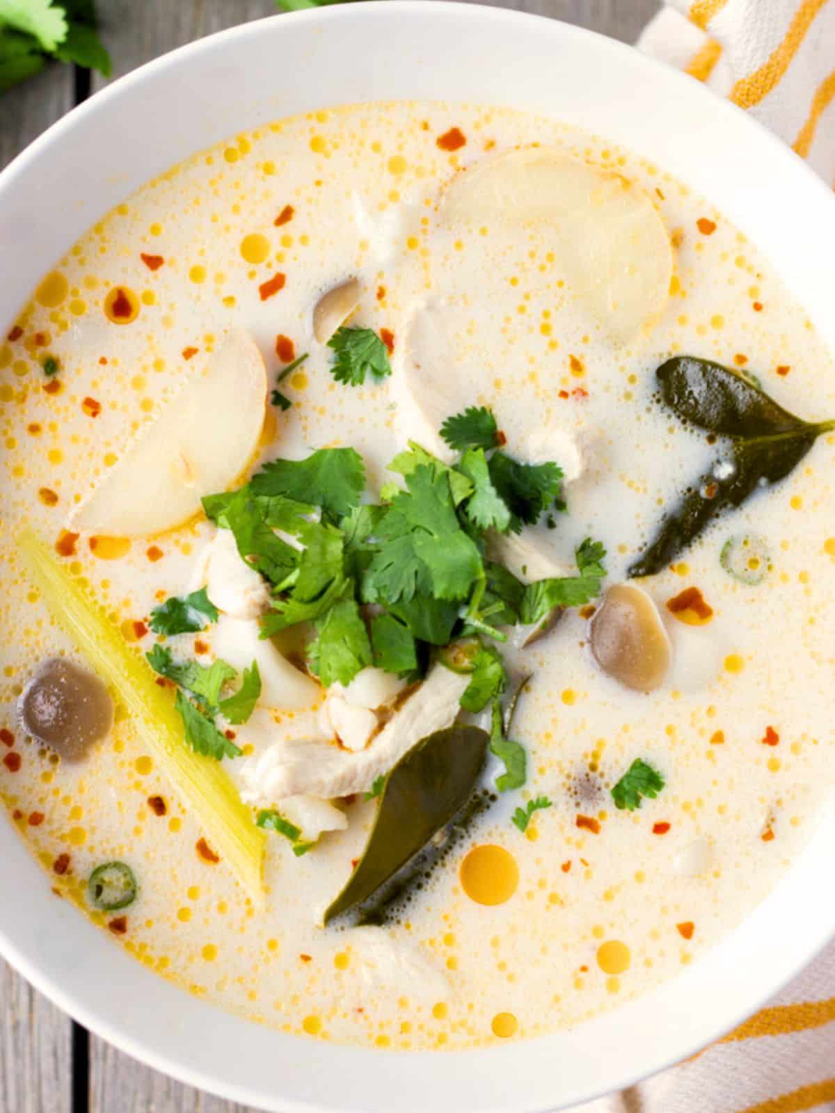 Overhead view of tom kha gai in a white bowl.