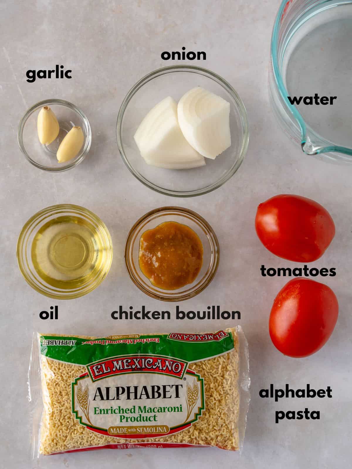 Ingredients with text, garlic, onion, water, oil, chicken bouillon, tomatoes, and alphabet pasta.