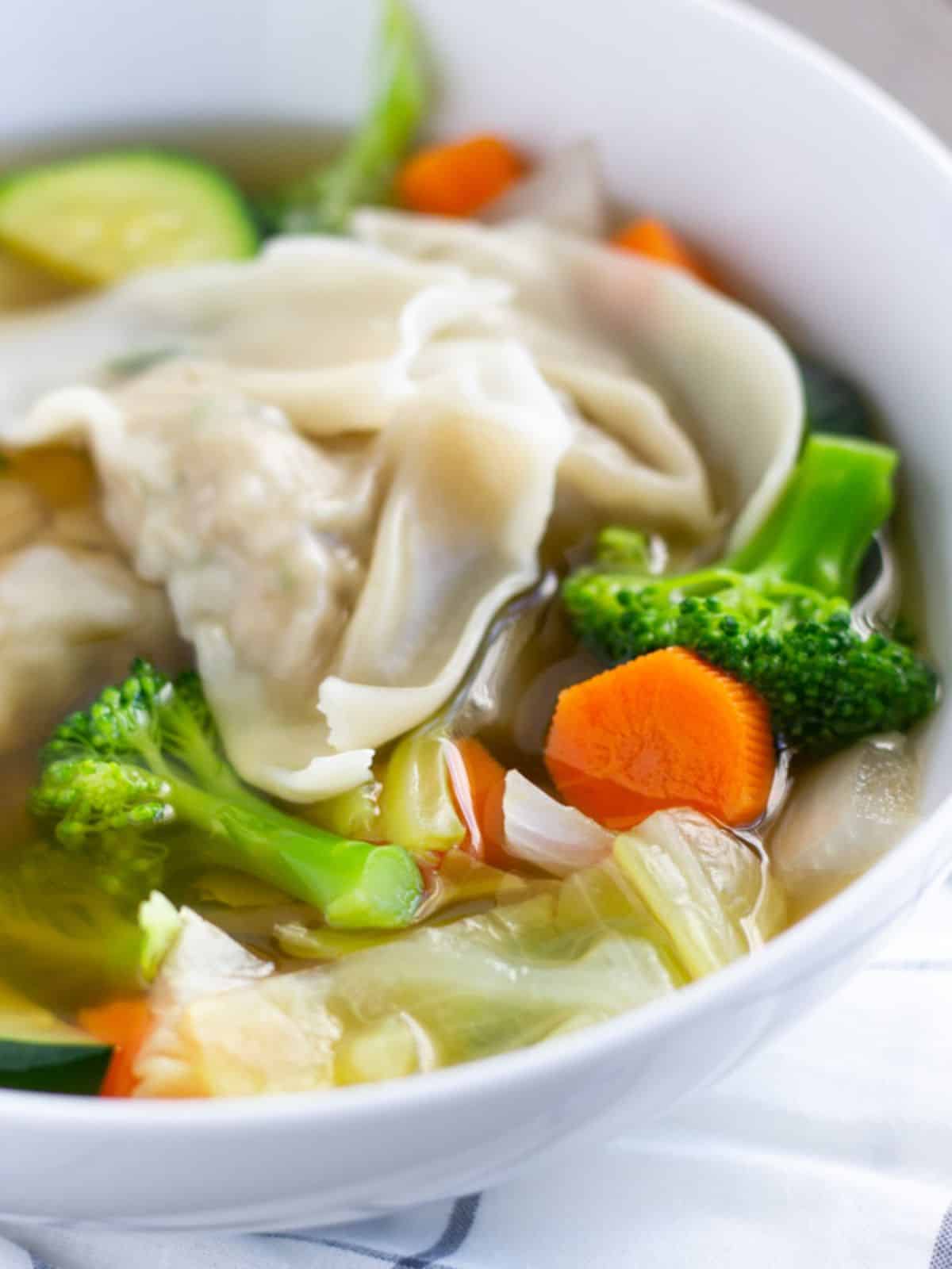Mixed vegetables and wontons on a bowl with broth.