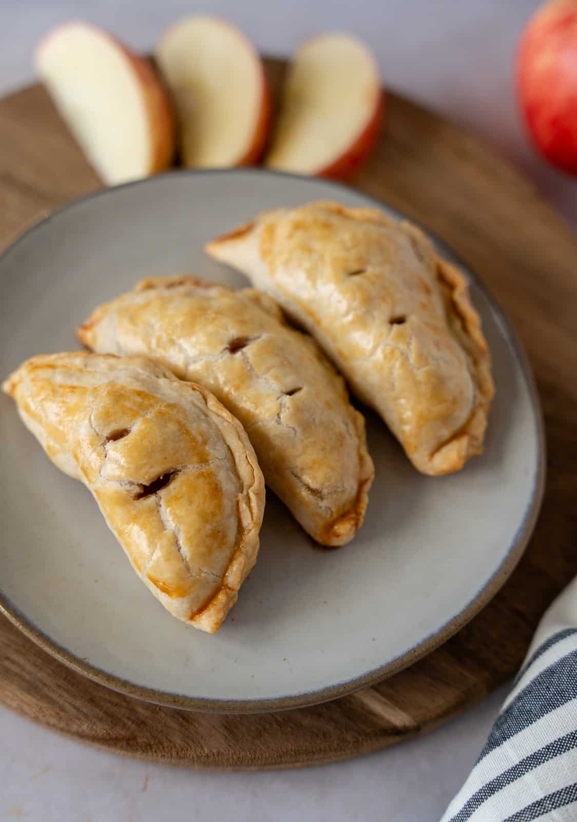 Three baked apple hand pies on a grey plate.