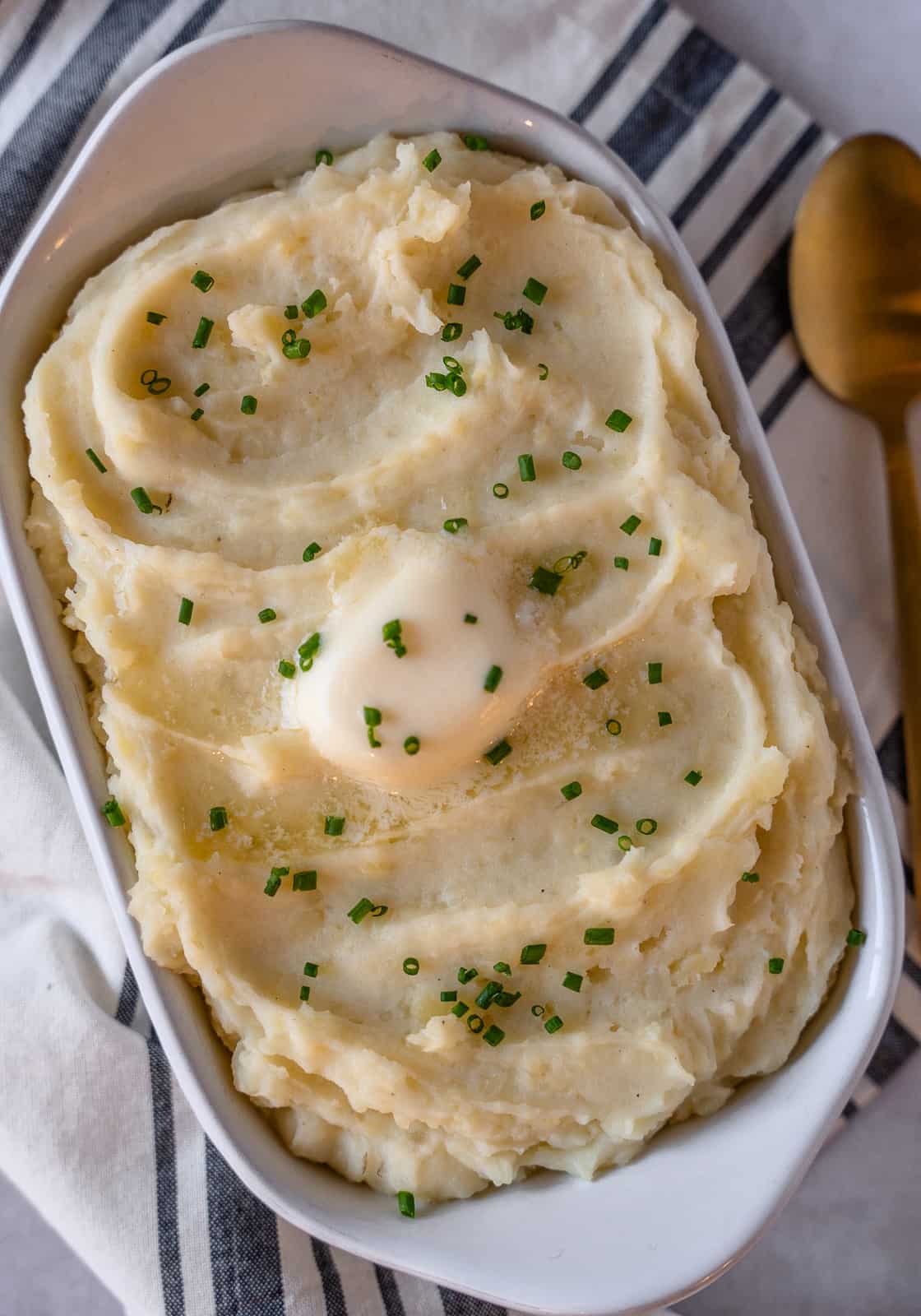 Overhead view of goat cheese mashed potatoes garnished with chives and a pat of butter.
