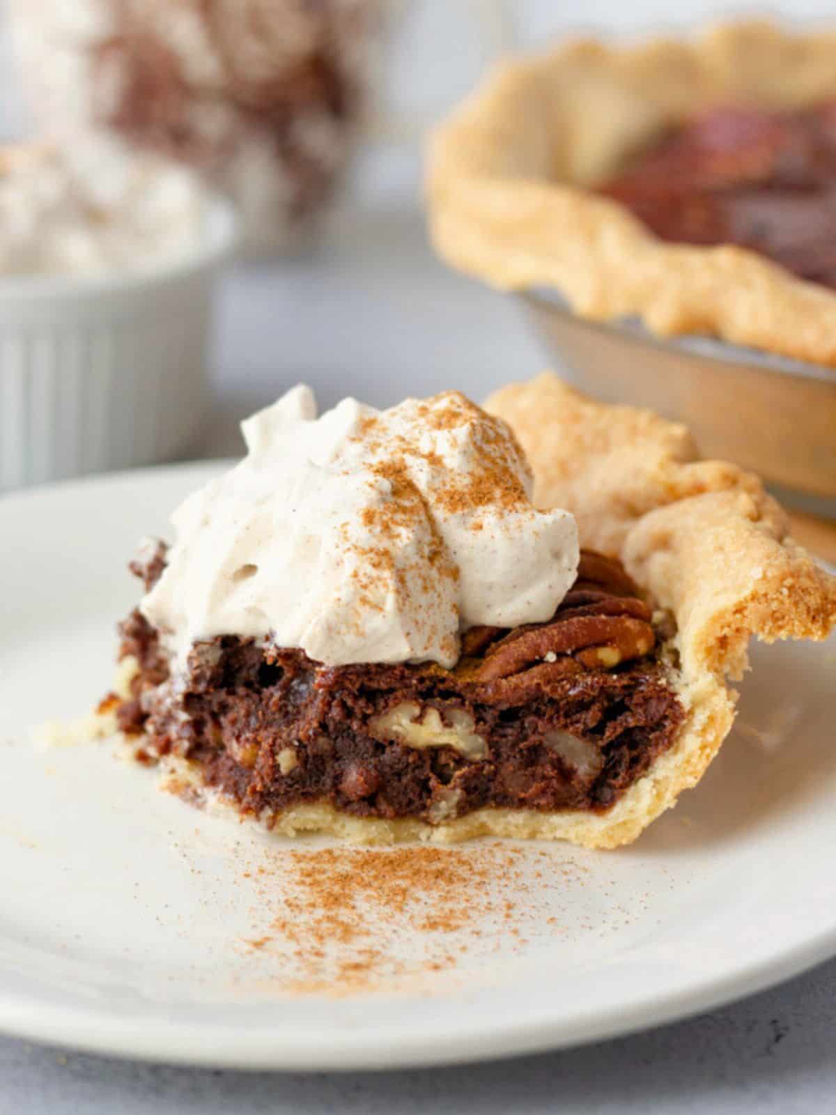 A slice of chocolate pecan pie on a plate with a dollop of whipped cream.