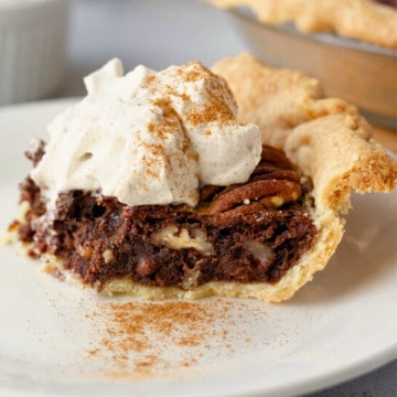 Feature image showing a slice of Mexican chocolate pecan pie on a plate with whipped cream.