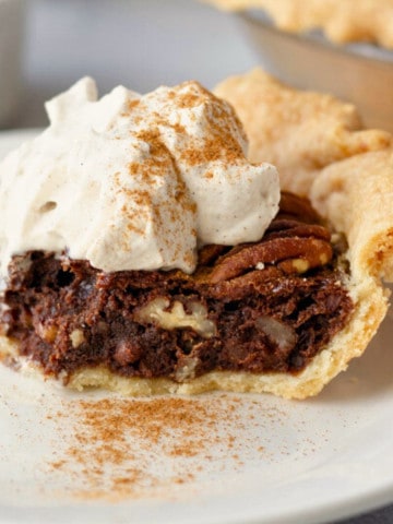 Feature image showing a slice of Mexican chocolate pecan pie on a plate with whipped cream.