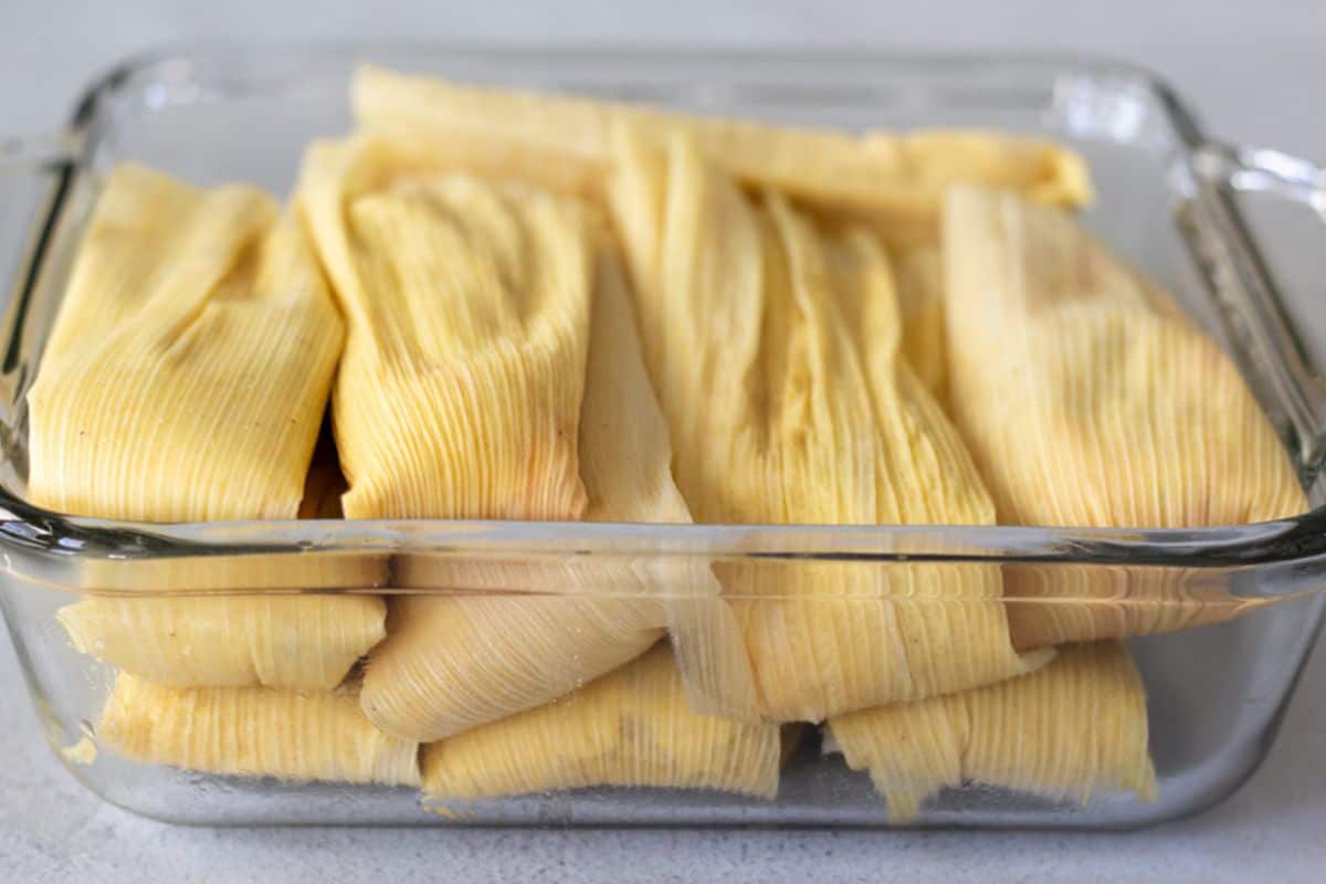 Uncooked tamales in a glass dish.