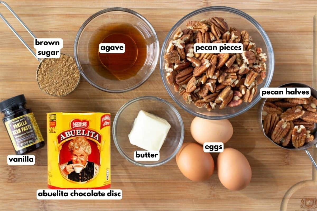 Ingredients with text, (brown sugar, agave, pecan pieces, pecan halves, vanilla, Abuelita chocolate, butter, and eggs.
