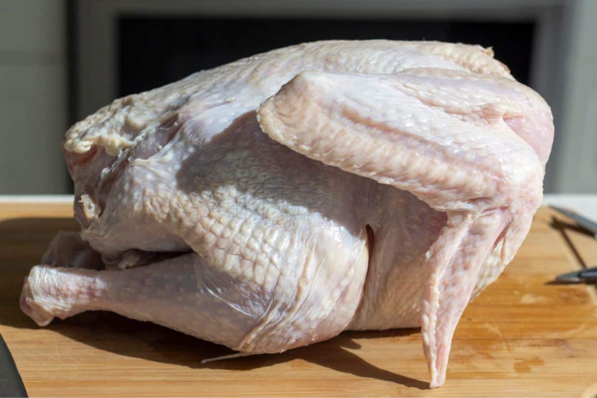 A whole uncooked turkey on a cutting board.