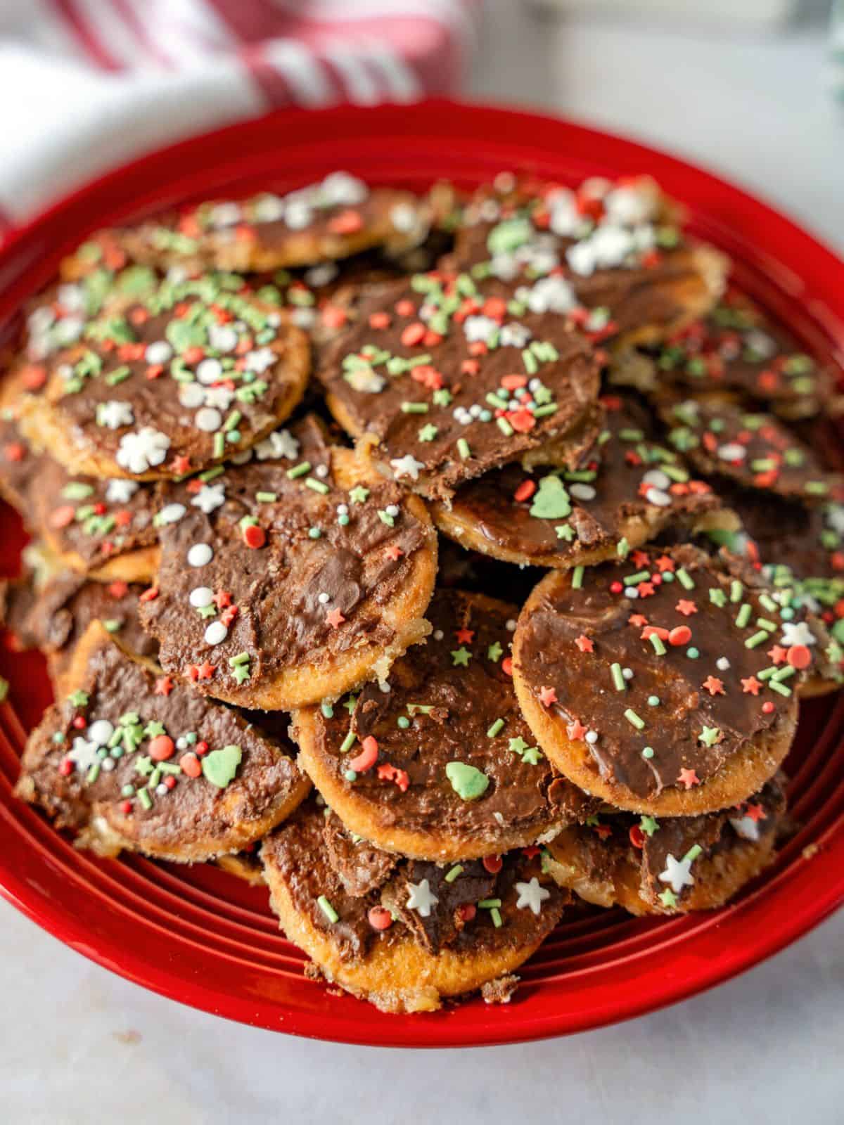 Cookie toffee on a red plate with Christmas sprinkles.