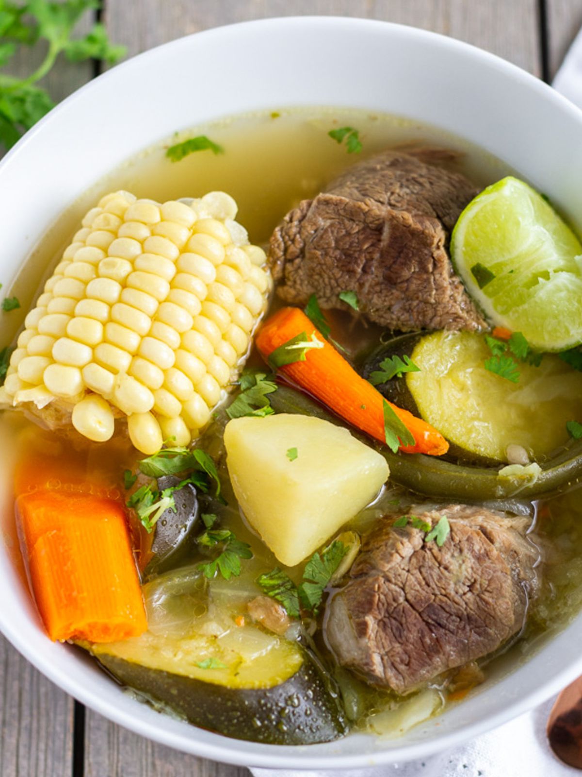 Mexican beef soup with vegetables in a white bowl.