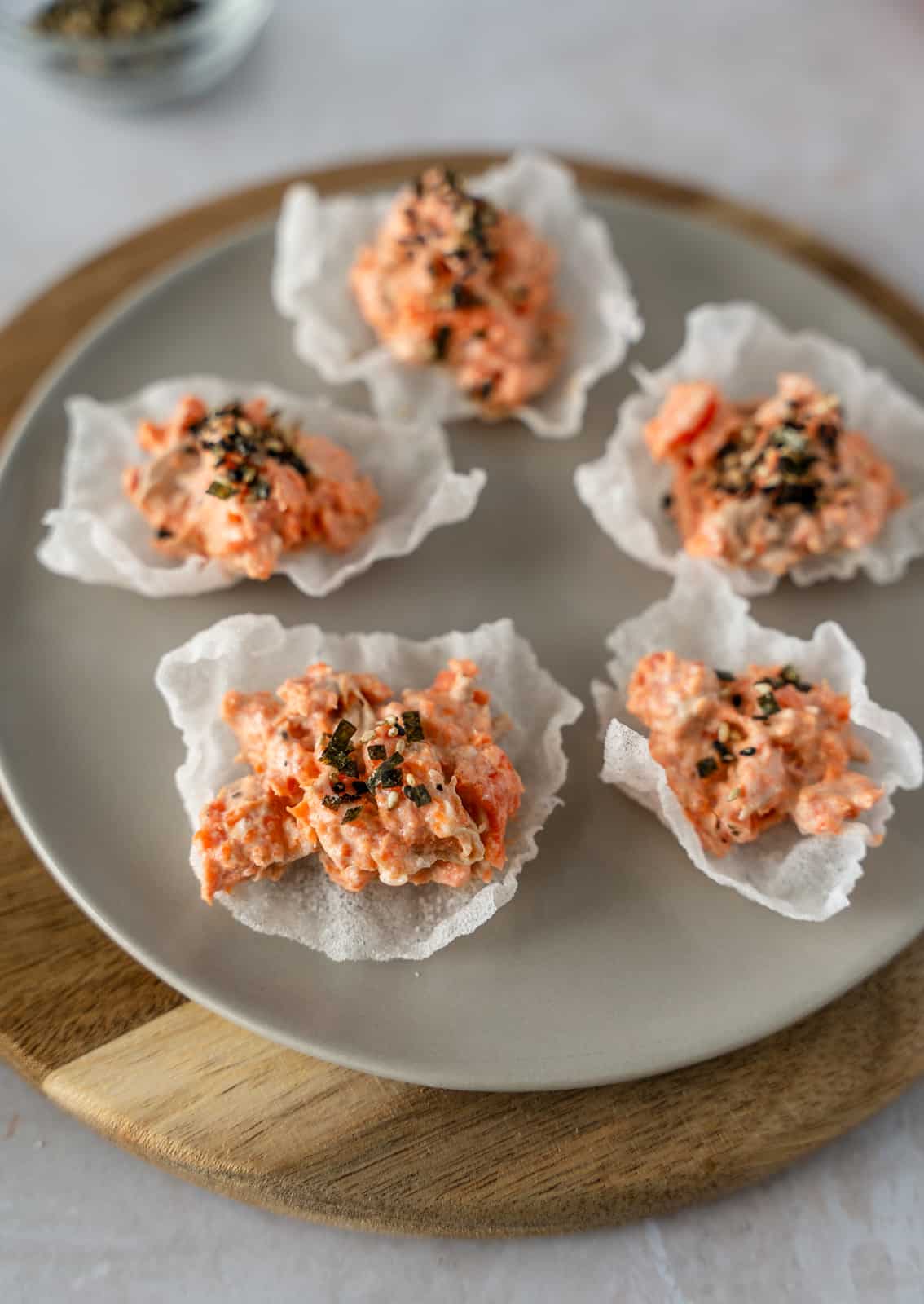 Salmon rice paper chips topped with furikake seasoning on a plate.