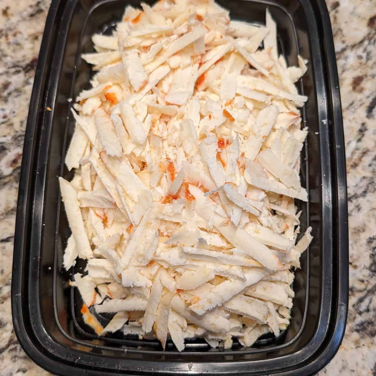 Shredded cheese in a black container.
