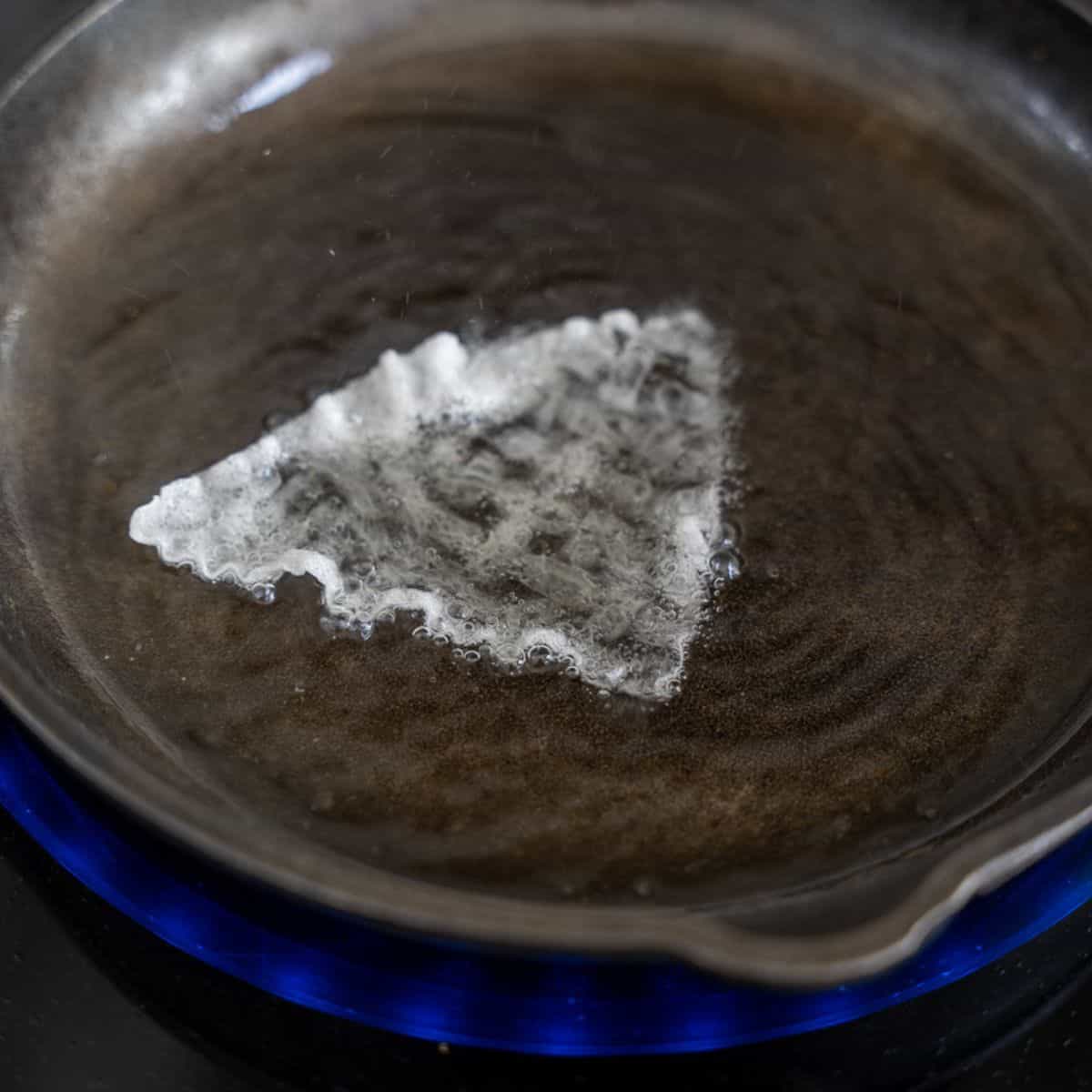 A piece of rice paper in a skillet with hot oil.