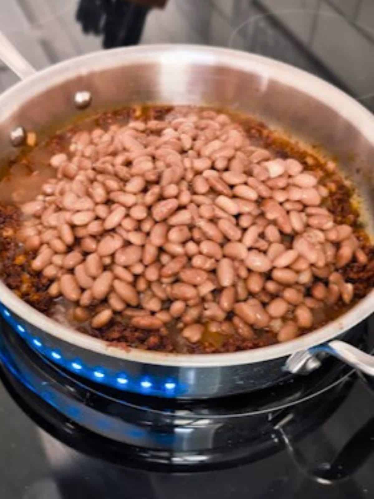 Chorizo and whole beans in a pan.