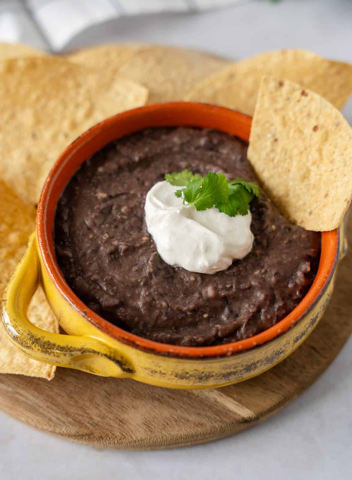 Black bean dip topped with sour cream and a tortilla chip.