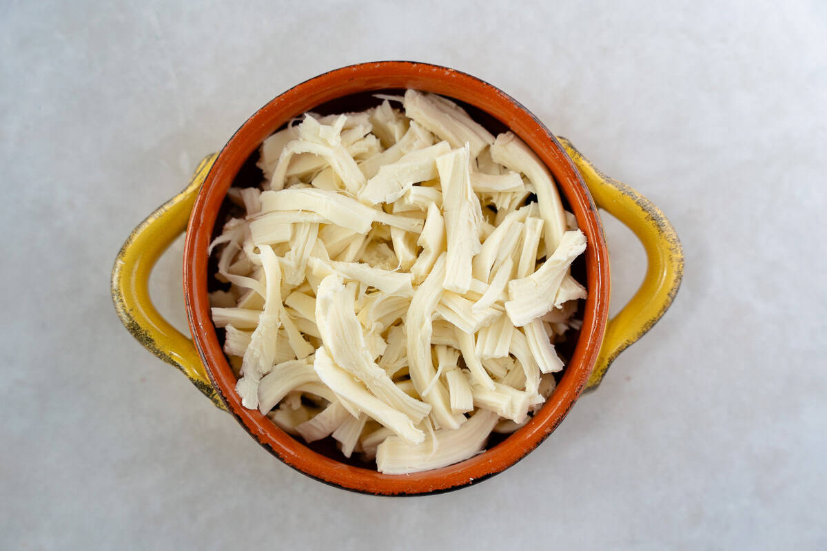 Shredded white cheese in a yellow ramekin.