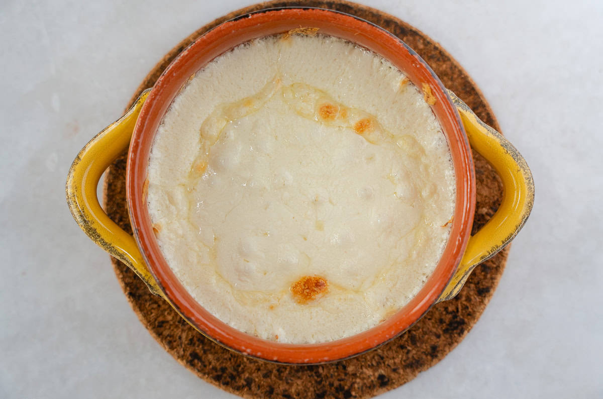 Melted cheese in a yellow ramekin.