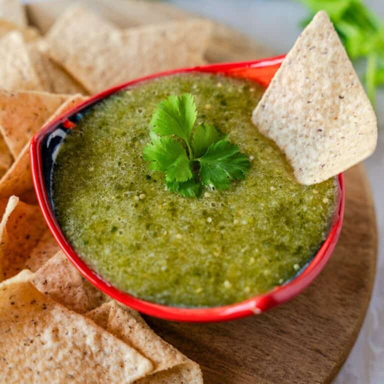 Feature image of salsa verde in a red bowl with a tortilla chip on the side.