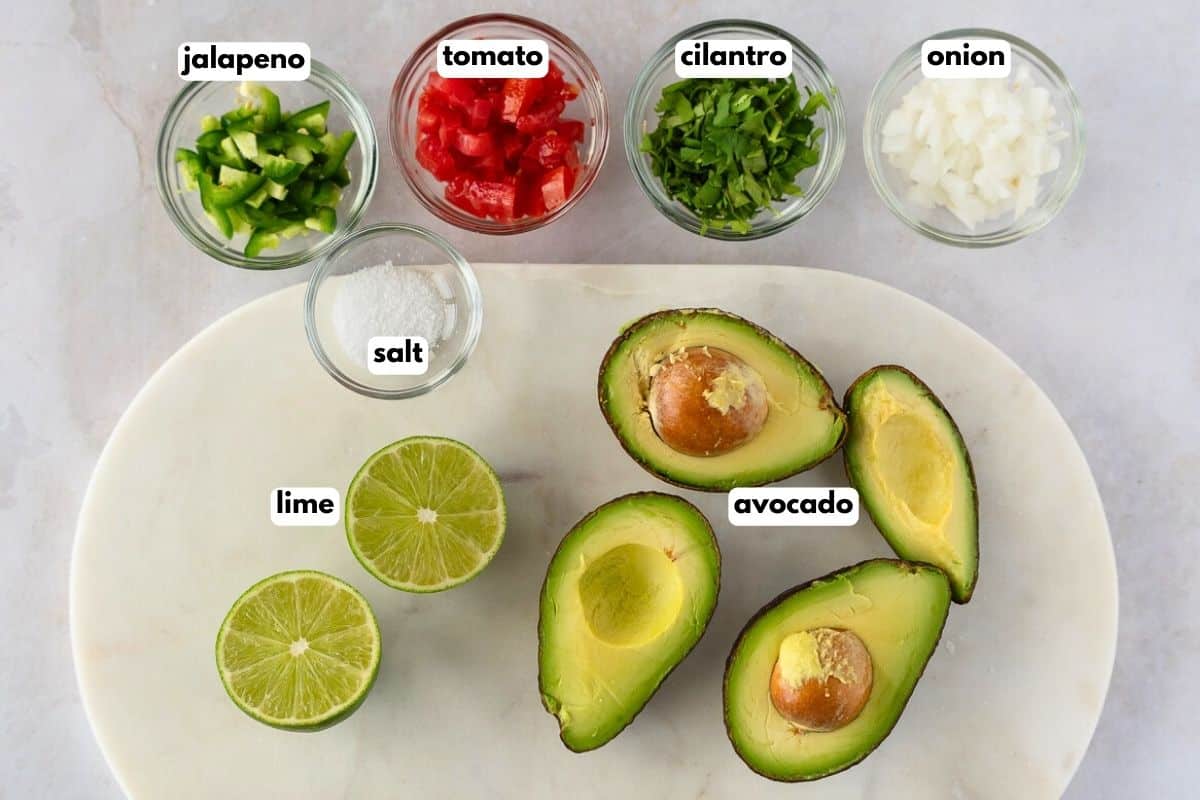 Ingredients for guacamole with text, jalapeno, tomato, cilantro, onion, lime, salt, and avocado.