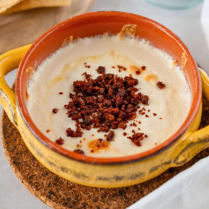 Feature image of queso fundido topped with chorizo in a yellow ramekin.