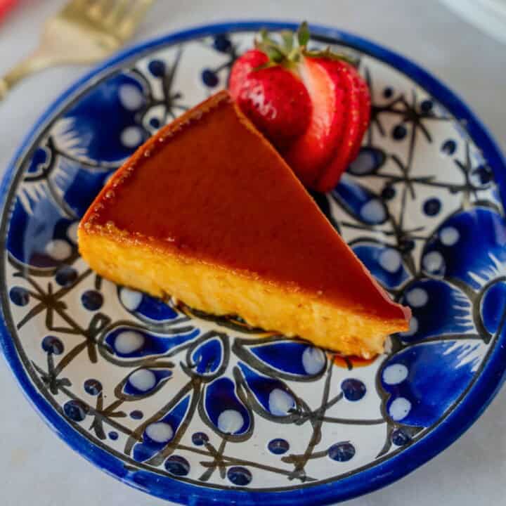 Feature image of a slice of flan on a blue plate with a strawberry garnish.