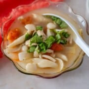 Feature image of Tom Yum Gai in a glass bowl with a white spoon.