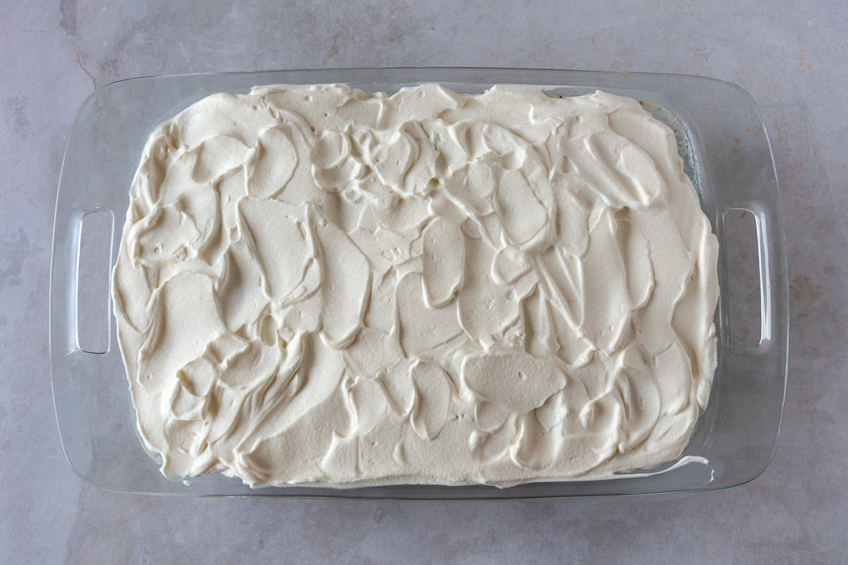 Cake in a glass pan with whipped cream topping.