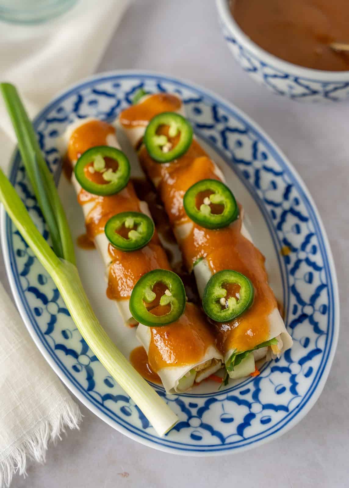 Paw pia sot or Thai fresh spring roll on a plate and garnished with sauce.