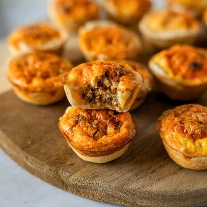 Feature image of mini chorizo quiche on a board with one that has a bite taken out.