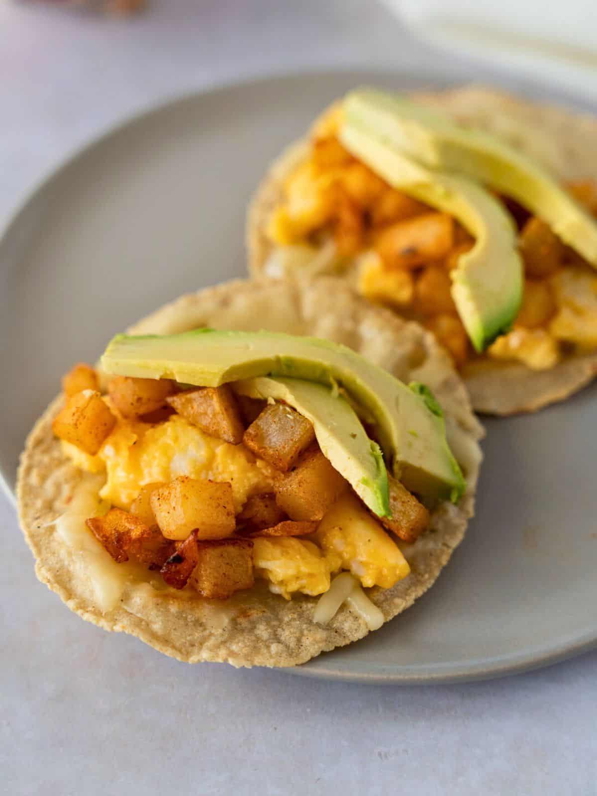 Potato, egg, and cheese tacos topped with sliced avocado.